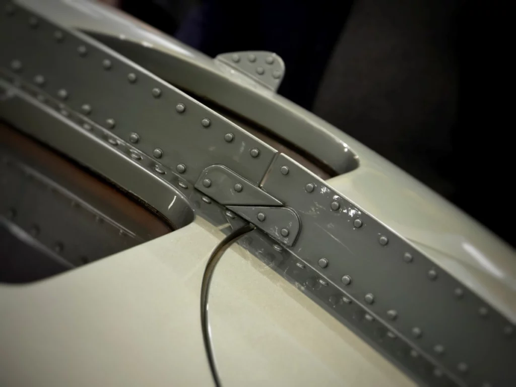 photographie, prise par pierre rollin, essences photographique, d'un détail de l'avant d'une voiture, mettant en évidence des rivets sur la surface métallique.